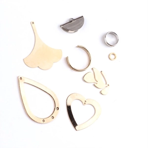 Makroansicht von Gold- und Silberginkgoblatt-, Herz- und Tropfen-DIY-Schmuckanhängern
