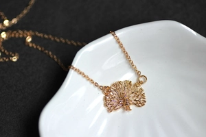 Detail of 18K gold-plated peacock pendant with intricate hollow design on white ceramic