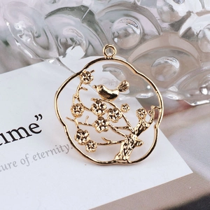 Detailed macro view of 18K gold-plated bird on a branch pendant with hollow engraving