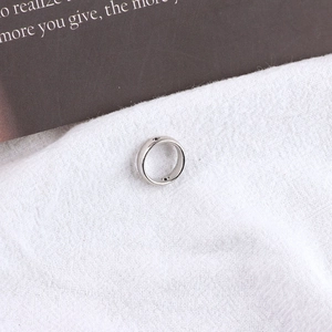 Nahaufnahme eines silbernen breiten Rings mit Schraubmuster-Dekor und industriellem Stil