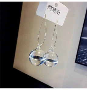 Close-up of a minimalist iridescent glass water ball drop earring on a white display card