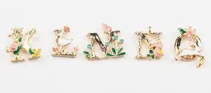Detail of floral enamel charms showing letters K to O with swan and bunny patterns
