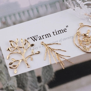 DIY gold-plated peacock and branch jewelry pendants displayed on a warm decorative card
