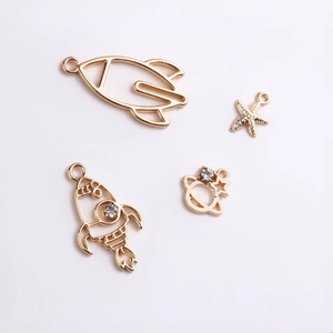 Detailed view of gold astronaut rocket and star charms for DIY jewelry making