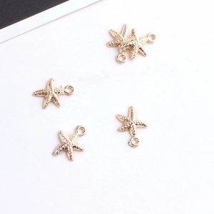Detailed view of five golden starfish charms with top rings for DIY jewelry making