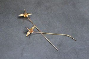 Détail des boucles d'oreilles traversantes grue origami dorée avec chaîne box et fini poli