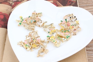 Detail of floral enamel alphabet charms in a white heart-shaped ceramic dish