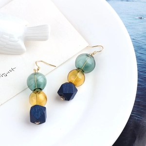 Detail of vintage long drop earrings featuring green, amber beads and blue geometric block