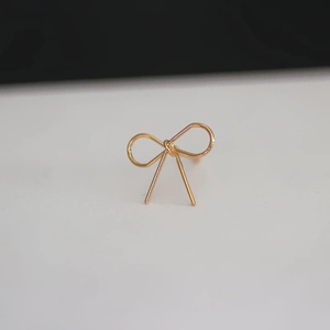 Close-up of minimalist gold-plated wire bow stud earring for DIY jewelry making