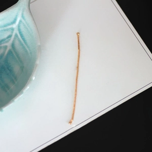 Detail of a thin gold-plated jewelry chain with bead structure for DIY earrings and necklaces