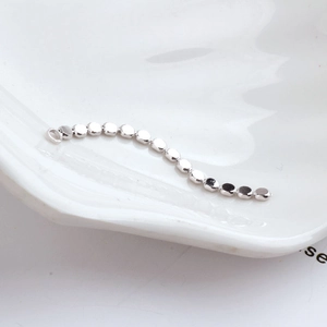 Polished silver beaded metal chain for jewelry making displayed on a white plate