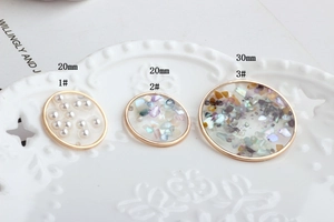DIY handmade resin charms with pearls and shells in golden metal frames on white plate