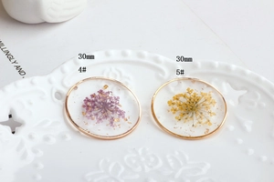Detail view of 30mm round gold frame resin charms with dried flowers and gold leaf