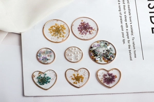 Detailed macro of DIY handmade resin pendants with dried flowers and gold foil elements