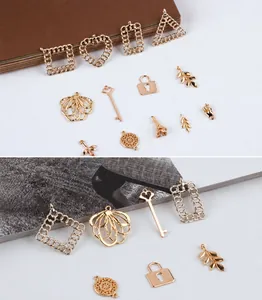 Close-up of golden alloy DIY charms featuring heart, key, lock, and leaf shapes