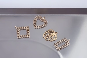 Close-up of golden hollow charms with chain texture and seashell shape for DIY jewelry