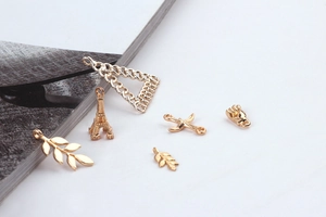 Detailed close-up of various gold alloy charms including Eiffel Tower and leaf shapes for DIY