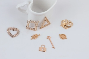 Close-up of assorted gold alloy charms including heart, key and lock jewelry findings