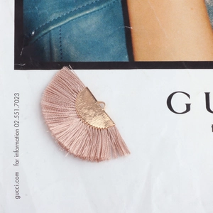 Detailed view of light pink silk tassel charm with golden metal cap for DIY jewelry