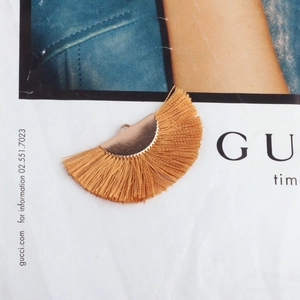Detail showing ginger yellow silk fringe pendant with a gold fan-shaped metal ring connector