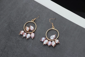 Detail of handmade gold branch circle earrings with five baroque pearls in pink hue