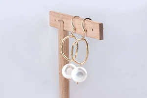 Detailed view of handmade irregular gold geometric rings and white round pearl earrings