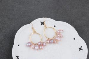 Detail of gold tree branch earrings with pink baroque pearls on a decorative white plate