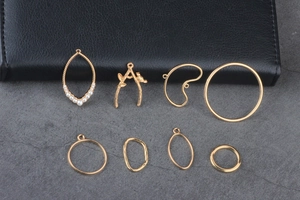 Variety of gold alloy jewelry charms including teardrop pearls and geometric branch designs