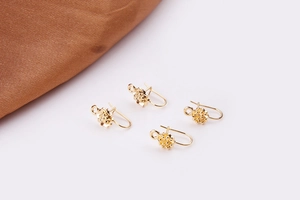 Close-up of four gold-plated flower U-shaped earring hooks for DIY jewelry making