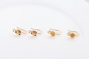 Detailed macro view of four gold-plated flower-shaped DIY earring hooks on white background