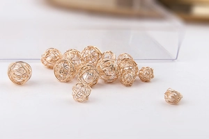 Vista macro de cuentas huecas envueltas en hilo dorado con perlas para crear joyería DIY