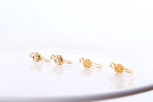Macro detail of four gold flower U-shape earring posts for DIY jewelry making