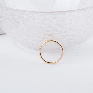 Close-up of minimalist gold alloy earring charm on a textured glass surface
