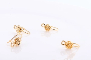 Close-up of four gold-plated flower-shaped U-pin earrings for DIY jewelry making