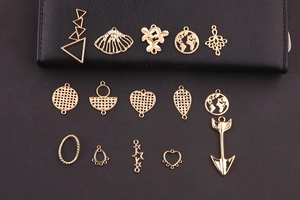 Primer plano de dijes dorados con formas de corazón y geométricas para joyería DIY