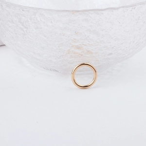 Polished gold minimalist round ring accessory next to a textured glass bowl