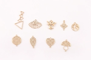 Detalle de colgantes geométricos de corazón y concha hechos de aleación dorada
