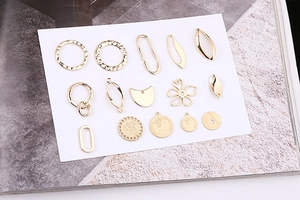 Macro shot of assorted golden metal charms for DIY jewelry making on white cardstock