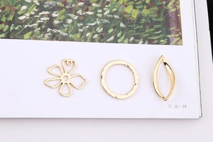 Close-up of golden irregular metal jewelry pendants including flower and leaf shapes