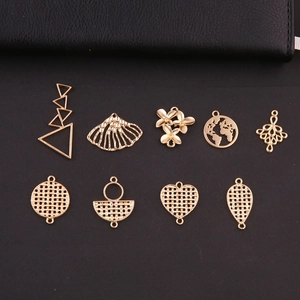 Primer plano de colgantes geométricos dorados con dijes de corazón y flores para joyería