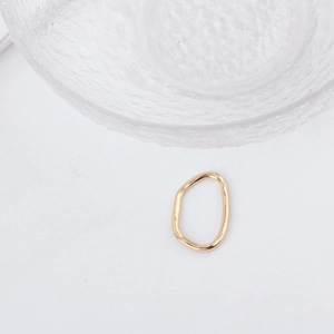 Detail of irregular wave gold alloy ring with unique hammered texture on white surface