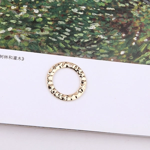 Detail of round golden metal charm with hammered texture for DIY jewelry making