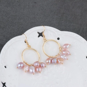 Handmade gold hoop earrings featuring irregular pinkish-purple freshwater pearl charms