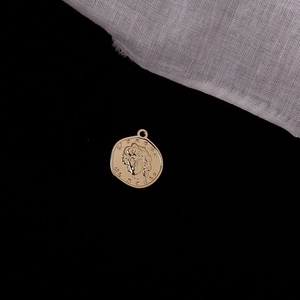 Macro shot of gold vintage coin pendant with relief carving on a dark background