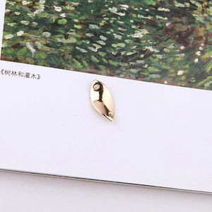 Macro detail of golden leaf-shaped metal charm with double holes for DIY jewelry
