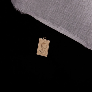 Macro detail of golden rectangular coin pendant with Queen Elizabeth II embossed design