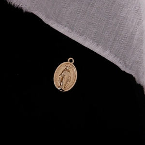 Macro detail of oval gold Mary medallion pendant with religious embossed engraving