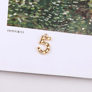 Detailed view of a gold plated number 5 metal pendant with faceted texture for jewelry DIY