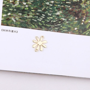 Detail of golden flower charm with dual loops for DIY jewelry making on art book