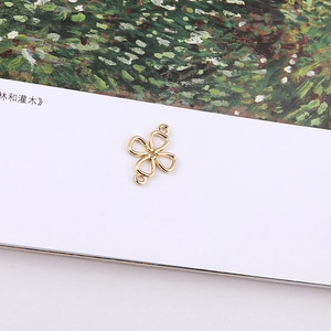 Close-up of golden metal four-petal flower connector with dual loops for DIY jewelry